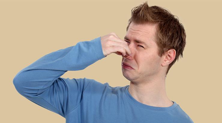 Person holder sig for næsen og trækker en grimasse som om noget lugter
